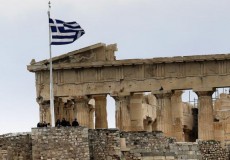 Tourists stand near the temple of Parthenon atop the ancient site of the Athens Acropolis on a cold and windy day