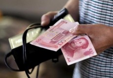 A customer holds a 100 Yuan note at a market in Beijing